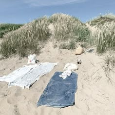 there is a towel and other items on the sand at the beach with grass in the background