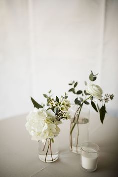 two vases filled with white flowers on top of a table