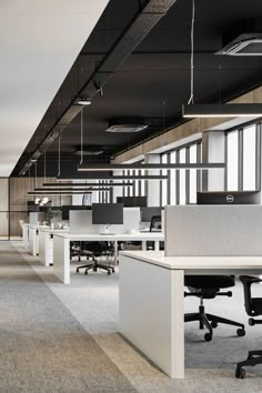 an empty office with desks and chairs in the middle of it, along with hanging lights