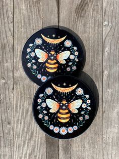 two black plates with bees and flowers painted on them