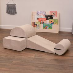 a couch made out of cardboard sitting on top of a hard wood floor next to a book shelf