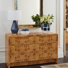 a blue vase sitting on top of a wooden dresser next to a mirror and lamp