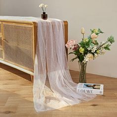 a vase filled with flowers next to a white cloth draped over an old fashioned radio