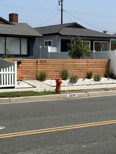 a red fire hydrant sitting on the side of a road next to a fence