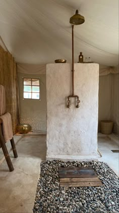 an outdoor shower in the middle of a room with rocks and gravel on the floor