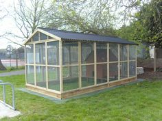 a small wooden structure with glass walls in the grass