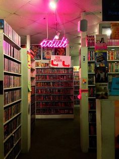 the inside of a book store with many books on shelves and neon signs above them