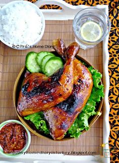 a plate with chicken, cucumbers and sauces on the side next to rice