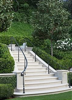 a set of white stairs leading up to a lush green hillside