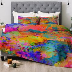 a bed with colorful comforters and pillows on it