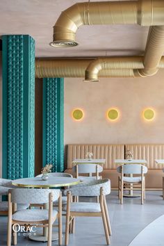 the interior of a restaurant with round tables and white chairs, gold accents on the walls