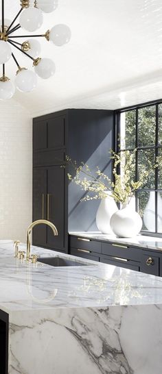 a kitchen with marble counter tops and black cabinets in the background, along with white vases