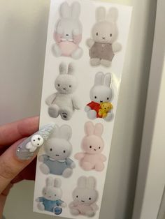 a hand holding a white sticker with many different stuffed animals on it's side