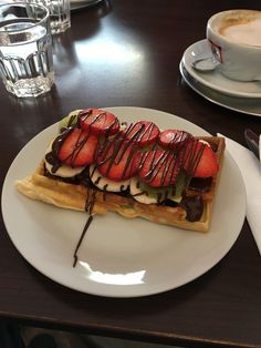 a waffle topped with strawberries and chocolate drizzled on top of it