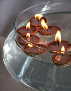 some lit candles are in a glass bowl