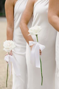 two bridesmaids in white dresses holding flowers