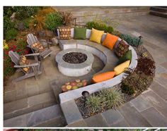 an outdoor fire pit surrounded by seating and plants