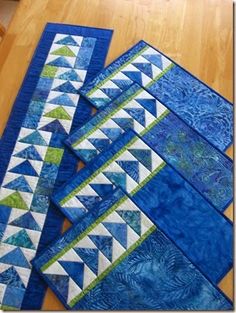 blue and green quilts laid out on the floor in front of a wooden table