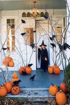 a man dressed as a witch standing in front of a house with pumpkins on the porch