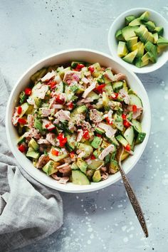 a bowl filled with cucumber and chicken salad next to another bowl full of vegetables