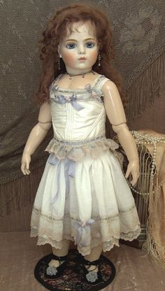 the doll is wearing a white dress with blue trimmings on it's chest