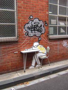 graffiti on the side of a building with a person sitting at a table