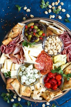 a platter filled with different types of cheeses and meats on blue cloth