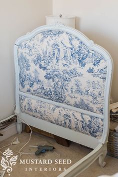 a blue and white headboard sitting on top of a floor next to a wall