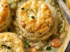 chicken pot pie with biscuits and vegetables in a casserole dish, ready to be eaten