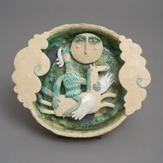 a ceramic bowl with an image of a woman and two birds in the center, on a gray background