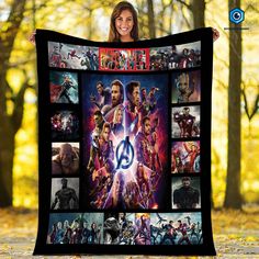 a woman holding up a blanket with the avengers movie characters on it in front of trees