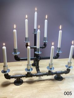 a large metal candle holder with many lit candles on it's sides and two rows of smaller ones in the middle