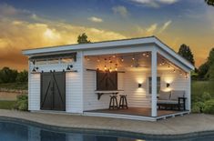 a small pool house with lights on the roof and patio furniture in front of it