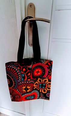 Tote bag in real African wax fabric. It measures 40 cm in height 35 cm wide And the webbing handles measure 52 cm. They are reinforced by a cross stitching on the bag (see Photo) Black Square Cotton Bag, Large Black Satchel With Top Carry Handle, Large Canvas Bags With Handles, Large Canvas Bag With Handles, Black Cotton Beach Bag For Travel, Red Fabric Shoulder Bag For Shopping, Black Cotton Travel Beach Bag, Black Square Canvas Bag For Errands, Large Black Bags With Leather Handles