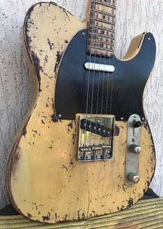 an old, worn out guitar sitting on top of a wooden table next to a wall