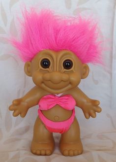 the troll doll has pink hair and is wearing a bathing suit on it's chest