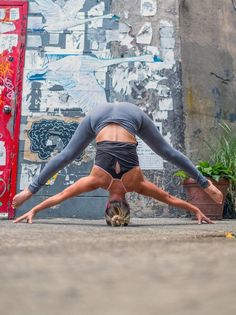 a woman doing a handstand in front of a wall