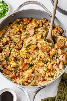 a pan filled with rice and shrimp next to some sauces on the side,