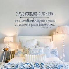 a bedroom with a white bed and blue wall decal on the wall above it is a quote that reads, have courage & be kind