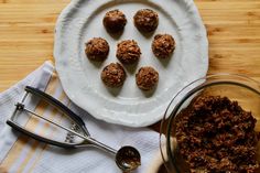 a white plate topped with meatballs next to a glass bowl filled with sauce on top of a wooden table