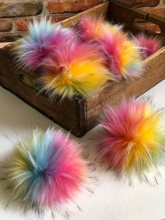 two colorful pom poms sitting on top of a table next to a wooden box