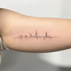 a woman's arm with a city skyline tattoo on the left side of her arm