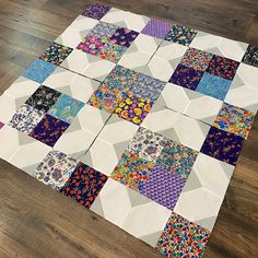 a patchwork quilt is laying on the floor in front of a wood flooring area