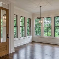 an empty room with three windows and wood floors