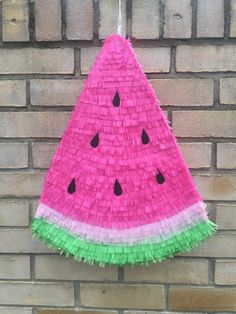 a watermelon pinata hanging on a brick wall