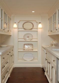 a kitchen with white cabinets and plates on the shelves