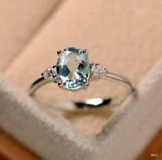 an engagement ring with a blue topaz surrounded by three white diamonds in a box