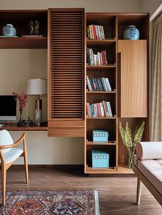 a living room filled with furniture and bookshelves next to a window on top of a hard wood floor