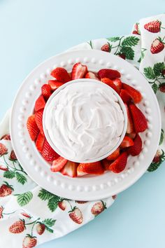 a white plate topped with strawberries on top of a floral table cloth next to napkins