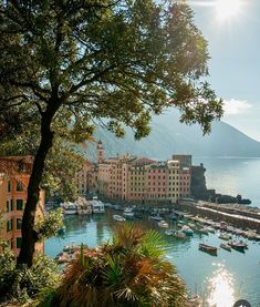 the sun shines brightly on boats docked in a bay next to buildings and mountains